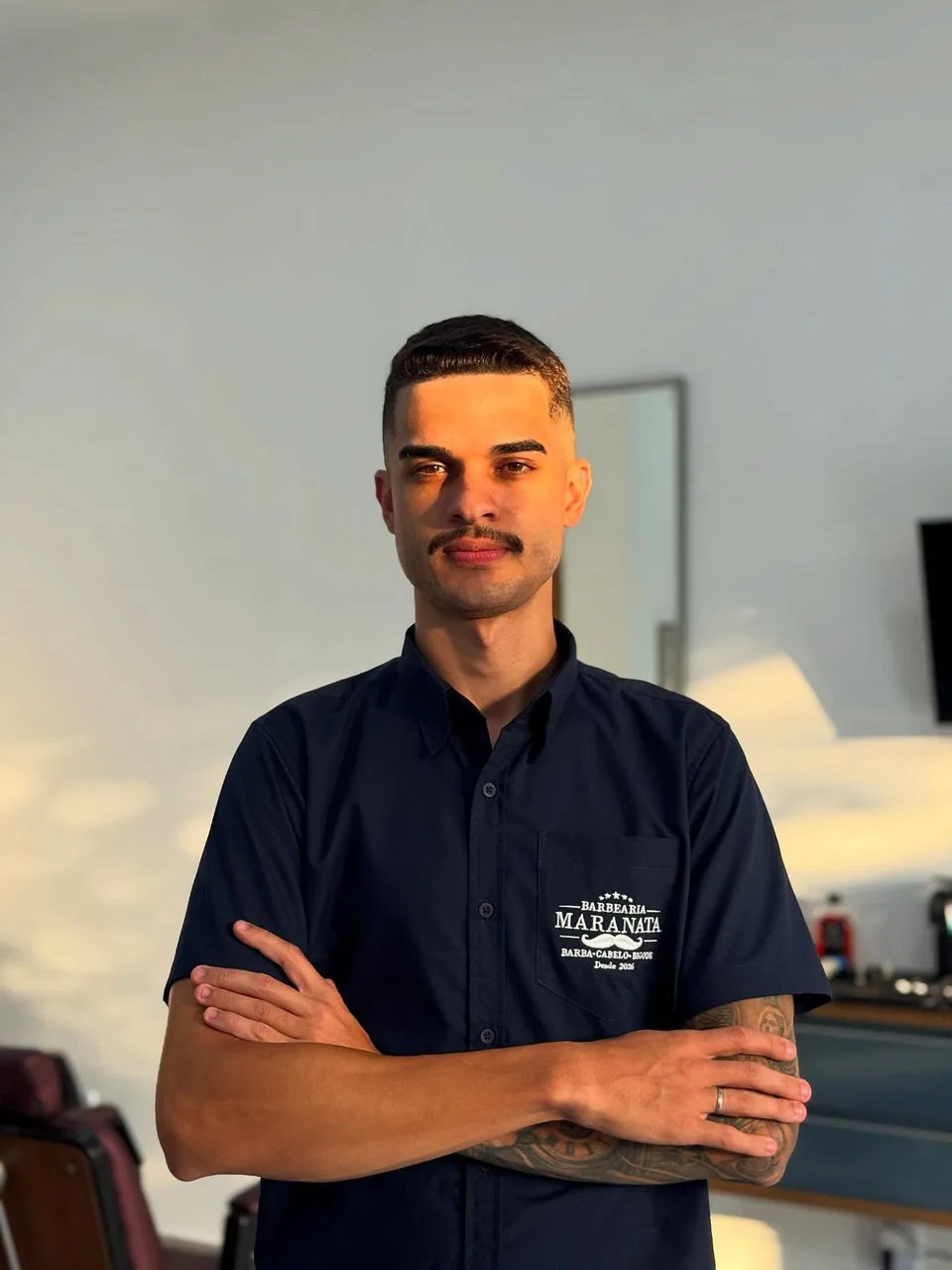 Retrato de David Santos usando o uniforme da Maranata Barbearia